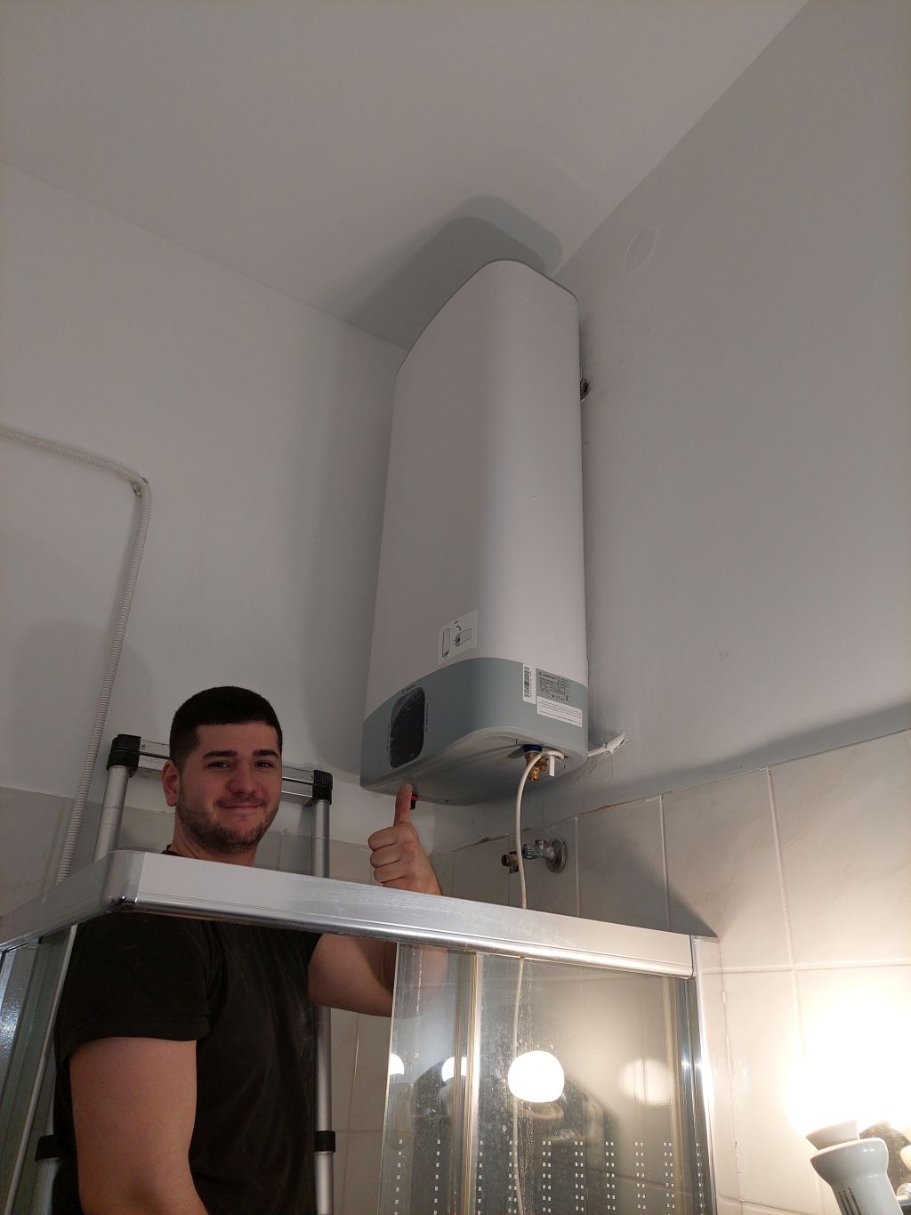 Szerelő az újonnan felszerelt fali villanybojler mellett egy budapesti fürdőszobában